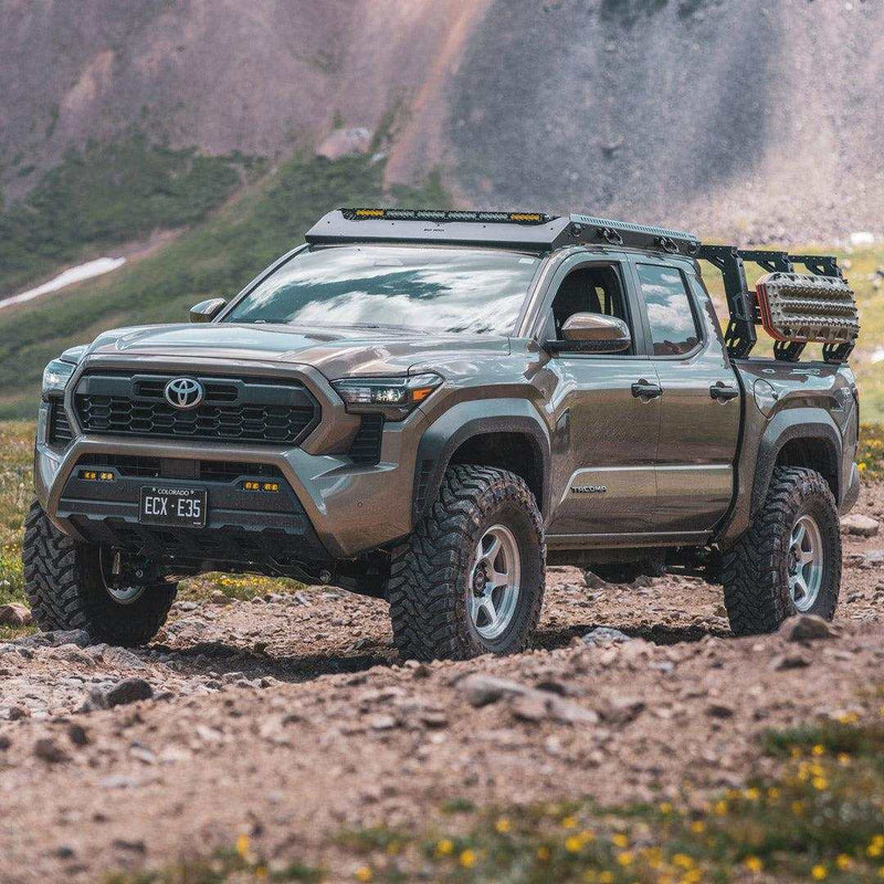 Load image into Gallery viewer, Toyota truck equipped with TracMOUNT Maxtrax Mount holding recovery boards on rocky terrain