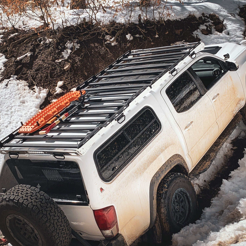 Load image into Gallery viewer, white off-road vehicle with black roof rack equipped with orange TracMOUNT Maxtrax Mount recovery boards in snowy terrain